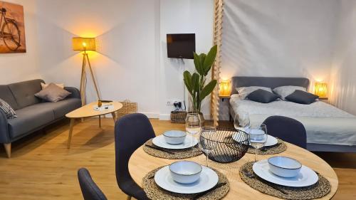 ein Wohnzimmer mit einem Tisch, Stühlen und einem Bett in der Unterkunft Magnifique appartement rénové plein centre-ville in Marmande