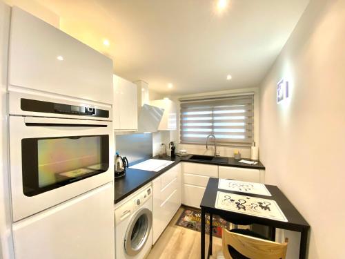 une cuisine avec des armoires blanches, un évier et une cuisinière dans l'établissement Eden Barmassa, à Villefranche-sur-Mer