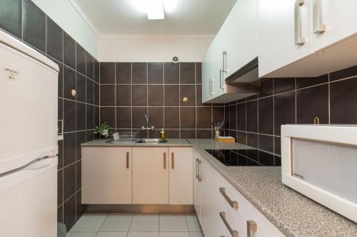 a kitchen with white cabinets and black tiles at Downtown & Beach in Albufeira