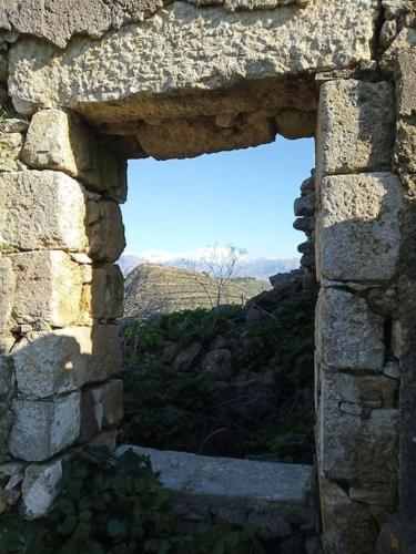 a window in a stone wall with a view of the sky at Traditional Creta stone house in serenity village in Vitsiliá