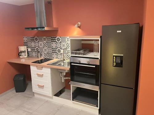 La cuisine est équipée d'un réfrigérateur noir et d'un évier. dans l'établissement Gites Terres De Provence, à Bourg-Saint-Andéol