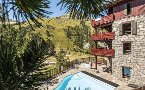 un complexe avec une piscine et un bâtiment dans l'établissement Arc 1950 - Auberge Jérôme - 4 à 6p - 1 chambre et 1 coin montagne séparé, à Arc 1950