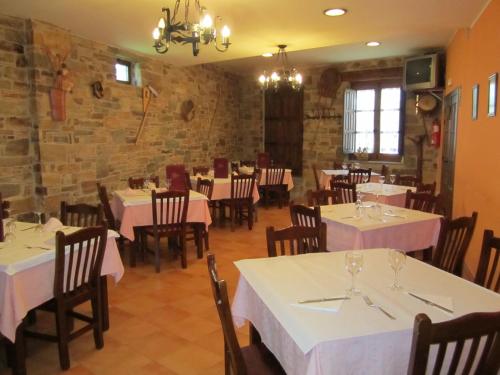 Hotel Rural El Molinero de Santa Colomba de Somoza في Santa Colomba de Somoza: مطعم بطاولات بيضاء وكراسي وجدار من الطوب