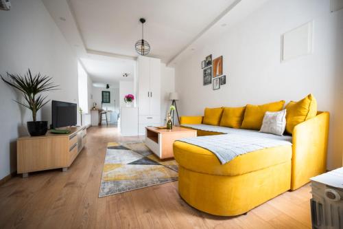 a living room with a yellow couch and a tv at Modern Studio Apartment in the Old Town in Sarajevo
