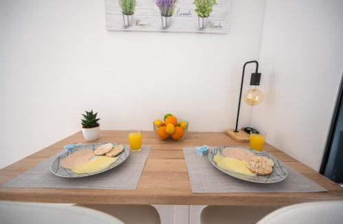 two plates of food on a wooden table with oranges at Modern Studio Apartment in the Old Town in Sarajevo