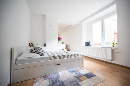 a white bedroom with a bed in a room with white walls at Modern Studio Apartment in the Old Town in Sarajevo