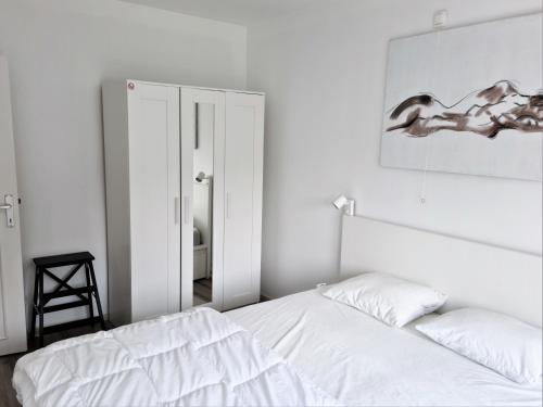 a white bedroom with a bed and a mirror at Appartement 2 chambres 200m plage Nieuwpoort Bad in Nieuwpoort