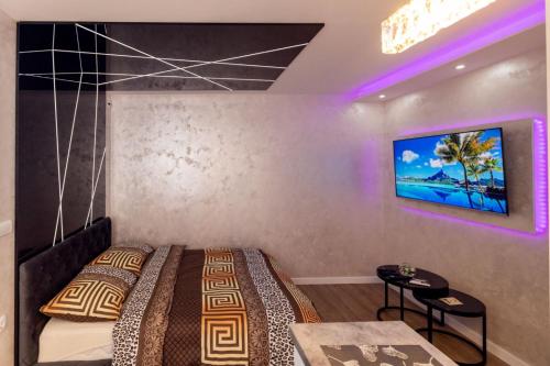 um quarto com uma cama e uma televisão na parede em Foča Apartmani "Story Lux" em Foca