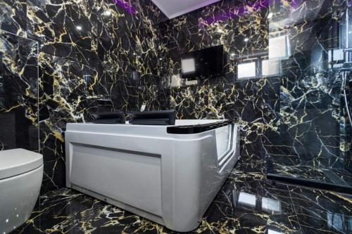 uma casa de banho com WC e uma parede em preto e dourado em Foča Apartmani "Story Lux" em Foca