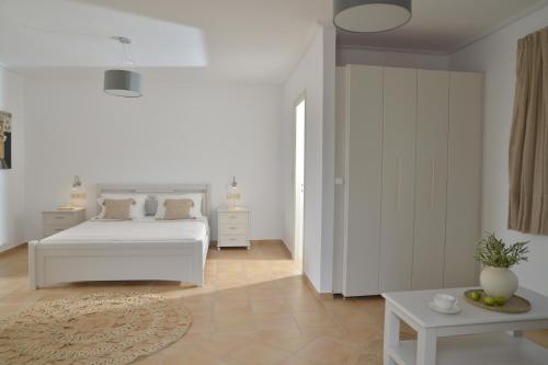 a white bedroom with a white bed and a table at Hotel Mediterranean in Stelida