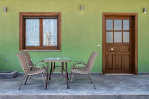 a table and chairs in front of a green wall at DANAI HOUSE 3 in Nea Roda