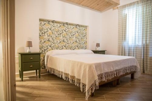 a bedroom with a bed and two tables and a wall at Casale De Filippo in Maratea