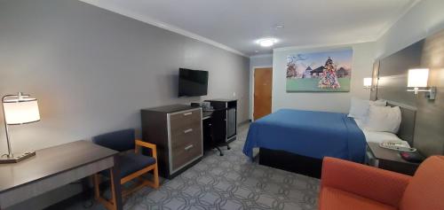 a hotel room with a bed and a desk and a tv at Ambassador Inn and Suites in South Yarmouth
