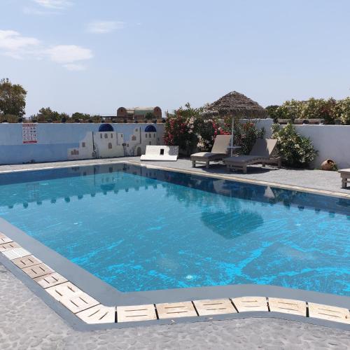 a large swimming pool with lounge chairs at Sagma Central Rooms in Perissa