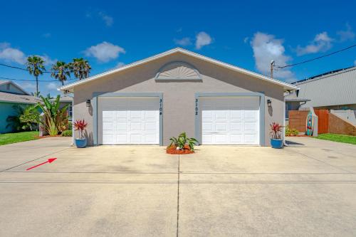 a house with two garage doors in a driveway at Unique Balinese Home with Fire Pit and Private Fenced Yard! 30 Seconds to the Sand! in New Smyrna Beach