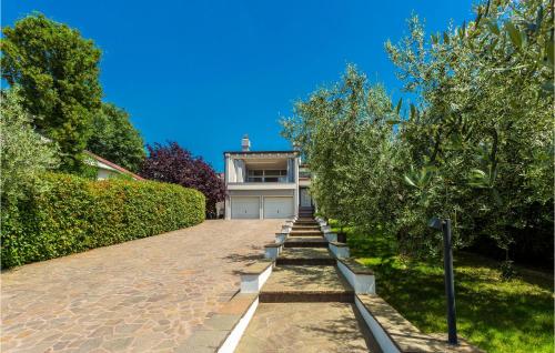 a brick driveway with trees in front of a house at Nice Home In Njivice With Jacuzzi in Njivice