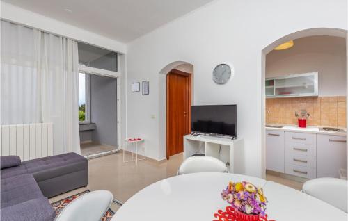 a white living room with a table and a tv at Nice Home In Njivice With Jacuzzi in Njivice