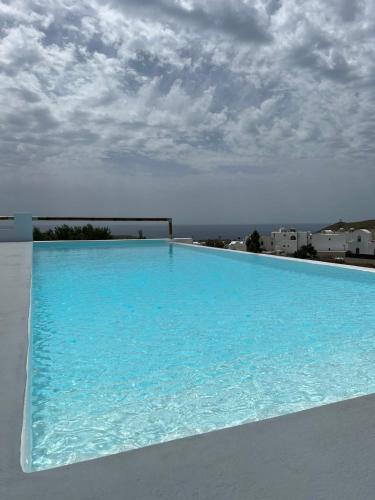 a large blue swimming pool with a cloudy sky at Acrothea Suites and Villas - Akrotiri Caldera - Santorini in Akrotiri
