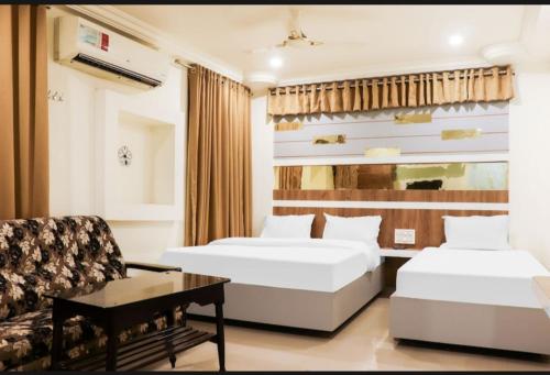 a hotel room with two beds and a chair at Hotel Menaka in Vijayawāda