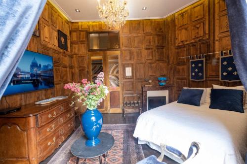 Un dormitorio con una cama y un jarrón con flores. en La Suite des Consuls en Sévérac d' Aveyron