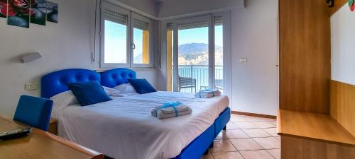 a blue bed in a room with a large window at Hotel Casa Marinella in Malcesine