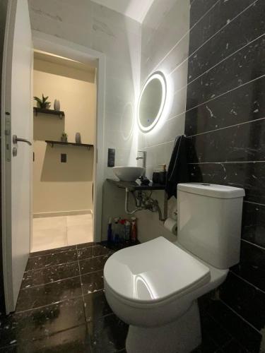 a bathroom with a white toilet and a black wall at I Love Home Mini in Kalamata