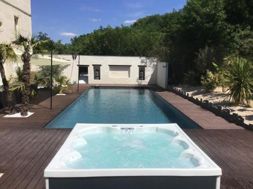 una piscina con bañera de hidromasaje en un patio trasero en Magnifique villa avec piscine chauffée et jacuzzi, en Anché