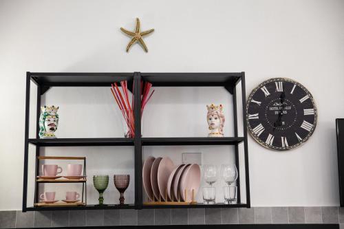 a black shelf with dishes and a clock on a wall at Il rifugio in Borgata in Syracuse