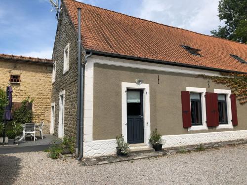 uma pequena casa de tijolos com portas vermelhas e uma mesa em Ferme de la Chapelle, entre terre et mer em Réty