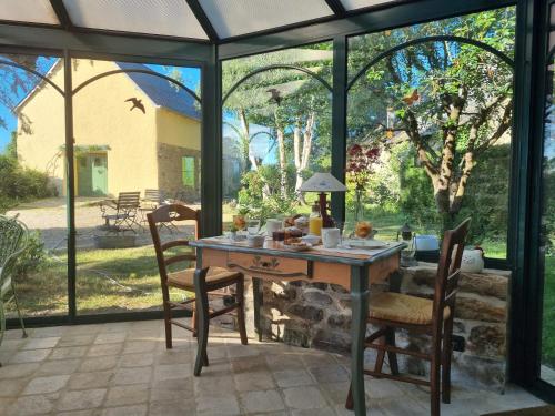 une véranda avec une table et des chaises dans l'établissement Les Berges de la Planchette, à Yvignac