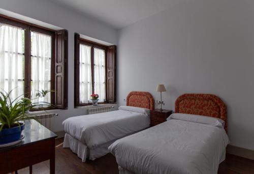 1 dormitorio con 2 camas, mesa y ventanas en La Villa del Pantano, en Olmedilla de Alarcón