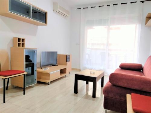 uma sala de estar com um sofá vermelho e uma televisão em ACV - Costa Marfil II - 2 linea planta 5 norte em Oropesa del Mar