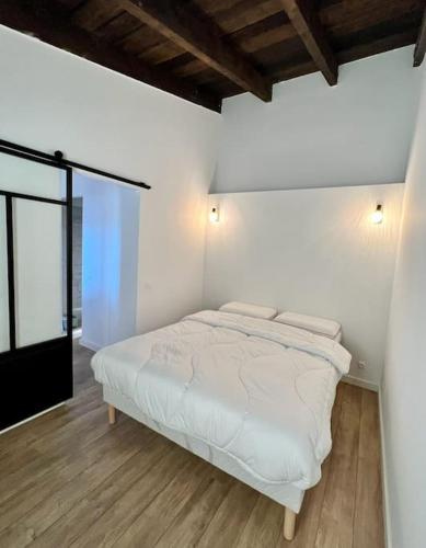 a bedroom with a white bed with two pillows at maison chaleureuse en plein coeur du centre ville in Saint-Florent