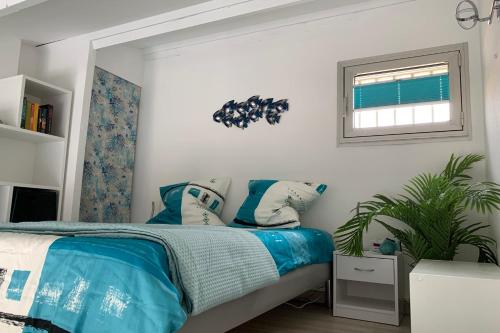 Schlafzimmer mit einem Bett mit blauer Bettwäsche und einem Fenster in der Unterkunft Cap d'Agde Naturiste Hélio-village 95 in Cap d'Agde