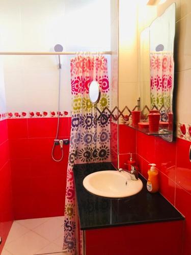 a red bathroom with a sink and a mirror at HOUSE l impérial pour vacance in Aourir
