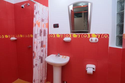 uma casa de banho vermelha com um lavatório e um espelho em Flor del Valle em Tarapoto