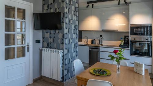 cocina con mesa y TV en la pared en Apartamentos Mar y Sol, en Luarca