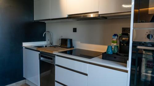 a kitchen with white cabinets and a sink at Apartamentos Mar y Sol in Luarca