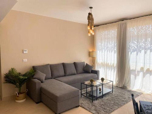 Lovely 1 Bedroom apt. At Mangroovy residence with free access to the Beach and Pools في الغردقة: غرفة معيشة مع أريكة وطاولة