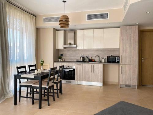 Lovely 1 Bedroom apt. At Mangroovy residence with free access to the Beach and Pools في الغردقة: مطبخ مع طاولة وكراسي في غرفة
