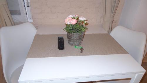 a vase of flowers on a table with a remote control at Cozy Rooms - BAÑERA HIDROMASAJE in Valencia