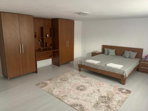 een slaapkamer met een bed, houten kasten en een tapijt bij Casa Deac in Sebeş