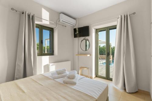 a white bedroom with a bed and a large window at Nora's Villa in Riglia