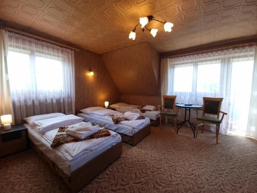 a room with three beds and a table and windows at Apartamenty Rodzinne in Witów