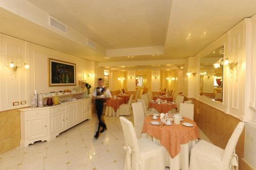 a woman walking through a restaurant with tables and chairs at Hotel Villa Rosa in Venice