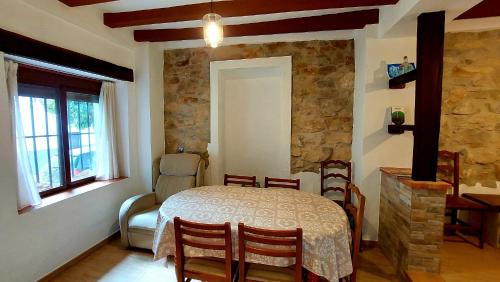 a dining room with a table and chairs and a stone wall at Vivienda Rural EL TORREÓN in Prado del Rey