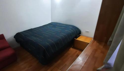 Cama azul en habitación con suelo de madera en Cabañas Habitainer 2, en Pucón