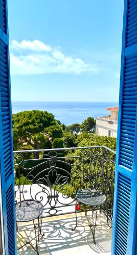 a balcony with tables and chairs and the ocean at Hotel Normandy in Cap d'Ail
