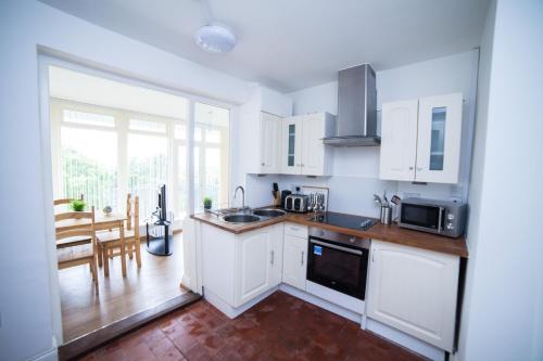 a kitchen with white cabinets and a large window at Highfield Road Apartment. in Rowley Regis