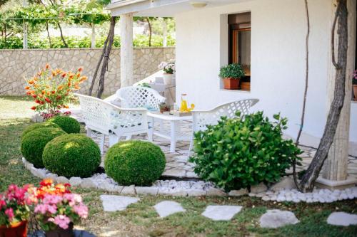 a patio with white chairs and a table and bushes at Markovic Village Apartments in Ulcinj